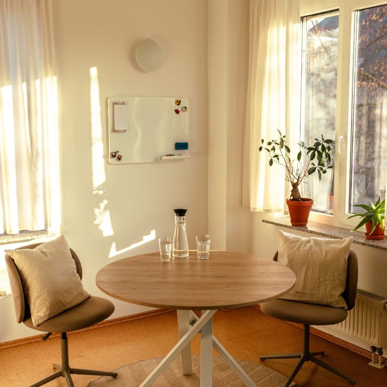 Beratungstisch LIBAVITAE Eine Glaswasserkaraffe steht neben zwei vollen Gläsern auf einem Holztisch.