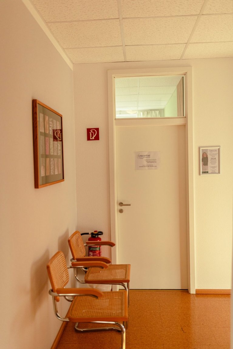 Wartebereich zur Praxis Wartebereich mit zwei Stühlen und einer Tür zu einem anderen Raum.
